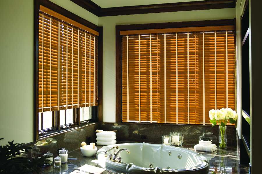 Brown wood blinds on large windows in a green bathroom